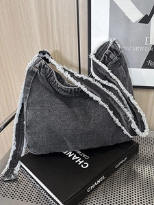 Borsa hobo vintage in denim lavato grigio scuro con bordi sfrangiati su libro