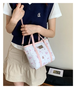 Detail view of white leather tote with pink piping and cute cartoon bear patterns