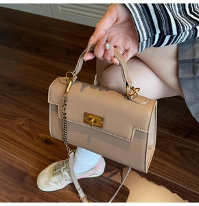 Detail of khaki pebbled leather Kelly bag with golden twist lock and chain strap side view