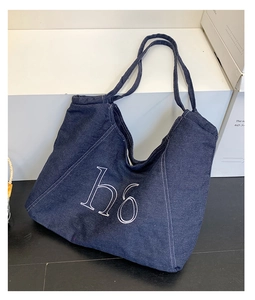 Detail of blue denim tote bag with white h6 embroidery and contrast stitching details