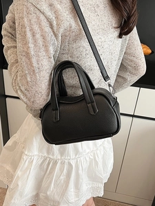 Sac à main minimaliste en cuir noir grainé avec forme courbée et double poignée élégante
