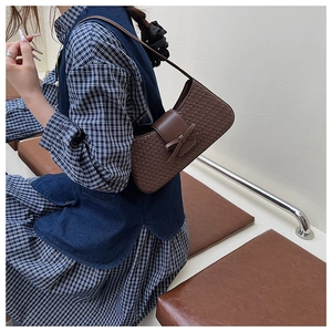 Vue détaillée du sac baguette tissé marron foncé avec noeud en cuir et bandoulière fine