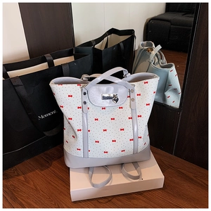 Detail of floral tote bag with red bow patterns, metallic heart charm and silver buckle