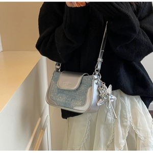 Detail of silver and glittery light blue crossbody bag with a star-shaped charm