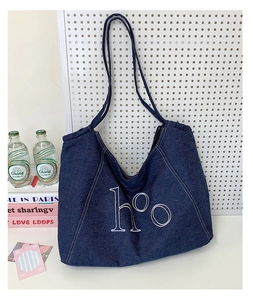 Detail of dark blue denim tote bag featuring white hºO letter print and sturdy shoulder strap