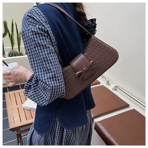 Detail of the woven texture and bow decoration on a brown underarm shoulder bag