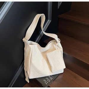 Close-up of cream textured tote bag with matching zipper pouch on wooden stairs