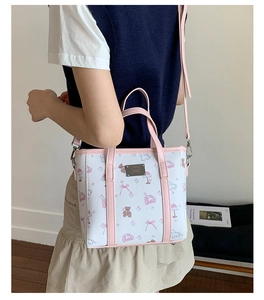 Detailed side view of bucket bag with cartoon bear print and pink leather straps