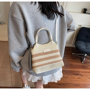 Detail of striped knit bucket bag featuring beige leather handle and woven texture