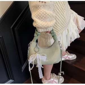 Detail of light green knitted handbag with pearl bow charm and cloud handle on stairs