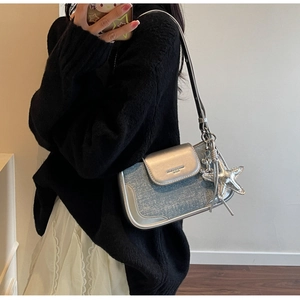 Detail of silver and blue patchwork shoulder bag with a metallic starfish charm