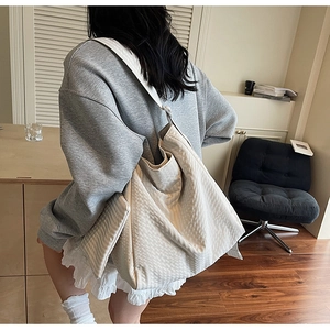 Detail view of large white tote bag with textured fabric on a model's shoulder