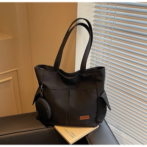 Detailed view of large black canvas tote bag with side pockets and a small round coin purse