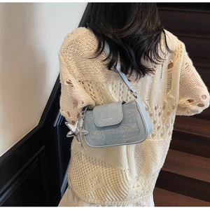 Close-up of light blue underarm bag with shimmering texture and silver star pendant