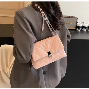 Pink quilted crossbody bag with silver chain strap worn over a stylish grey blazer