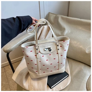 Close-up of white floral tote bag with red bows and heart pendant detail