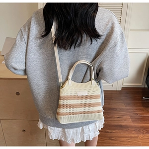 Detail of hand-woven beige and brown striped bucket bag with knit texture