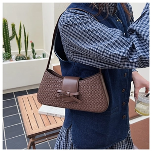 Detailed texture of dark brown woven baguette bag with a stylish 3D bow decoration