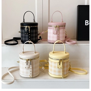 Detail view of cylinder bucket bags in four colors with textured grid pattern and gold hardware