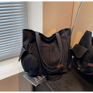 Close-up of black canvas tote bag showing side flap pockets and detachable coin purse pouch