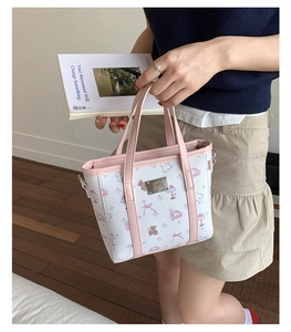 Close-up of printed mini tote bag with pink bear patterns and silver brand logo plate