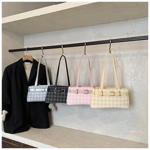 Row of four plaid shoulder bags in different colors hanging on display with a black blazer