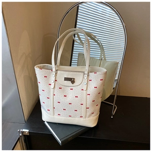 Detailed view of cream floral tote bag with red bow patterns and heart charm detail