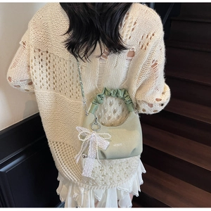 Detail of light green ruched handbag featuring white lace pearl bow and silver chain strap