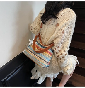 Détail d'un sac hobo tissé à rayures colorées avec bandoulière en cuir et breloque étoile