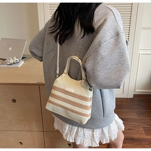 Close-up of beige knitted tote bag featuring a striped hollow design and leather handles