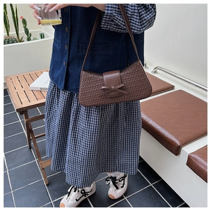 Detailed view of dark brown woven leather underarm bag with a cute bow on the flap