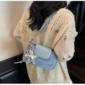 Detail of light blue glitter shoulder bag with silver star charm worn by a model