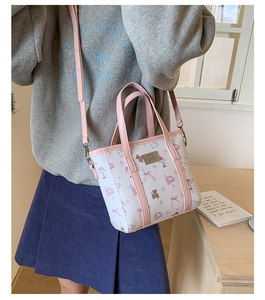 Detail of a white floral tote bag with pink straps and a cute cartoon bear print pattern