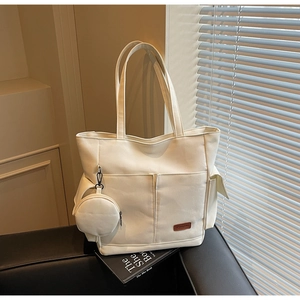 Detail view of large canvas tote bag with matching round pouch and brown leather logo tag