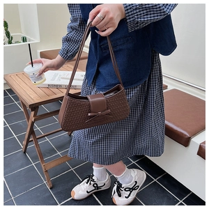 Detailed close-up of brown woven texture and leather bow decoration on the shoulder bag