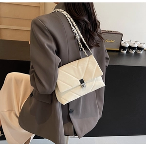 Detail view of beige velvet shoulder bag with V-quilted stitching and silver chain strap