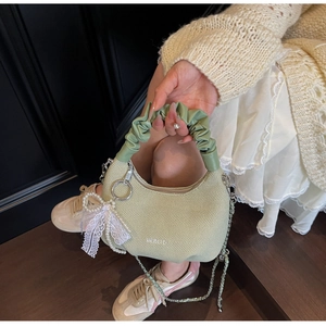 Detail of pistachio green pleated handle and lace pearl charm on herringbone handbag