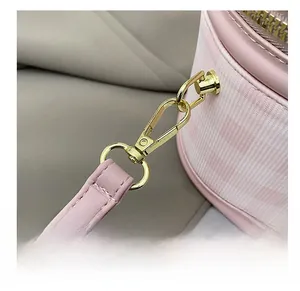 Close-up of golden metal hook fastener and pink leather strap on cylinder bag