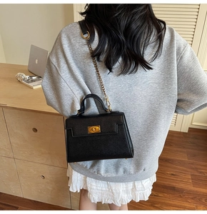 Detail shot of a black crossbody Kelly bag with gold chain strap in a lifestyle setting