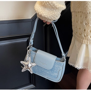 Close-up of light blue leather bag featuring silver starfish charm and magnetic buckle