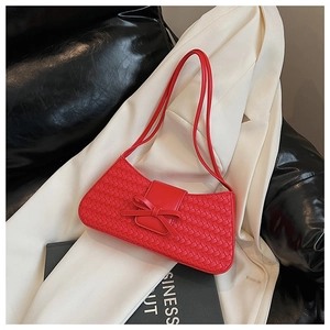 Close-up of red woven underarm bag featuring a delicate bow clasp and leather texture