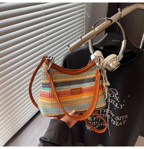 Détail d'un sac de plage tressé coloré avec des rayures multicolores et bandoulière en cuir