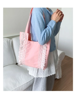 Detail of pink canvas tote bag with white lace ruffle edges on shoulder strap style