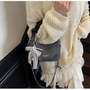 Detail of grey dumpling bag with black pleated handle and oversized lace bow charm