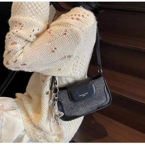 Detail of fabric crossbody bag with leather trim and silver star pendant on model