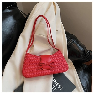 Detail of red woven underarm bag with a central bow knot and dual shoulder straps