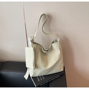 Detail of light green checkered tote bag with a matching hanging coin purse on a sofa