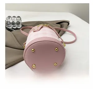 Detail shot of the pink plaid bucket bag's leather base with four golden protective studs
