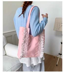 Detail of pink canvas tote bag featuring white lace trim and wide comfortable straps