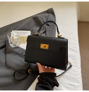 Detail of black crossbody Kelly bag with gold twist lock and saffiano texture leather